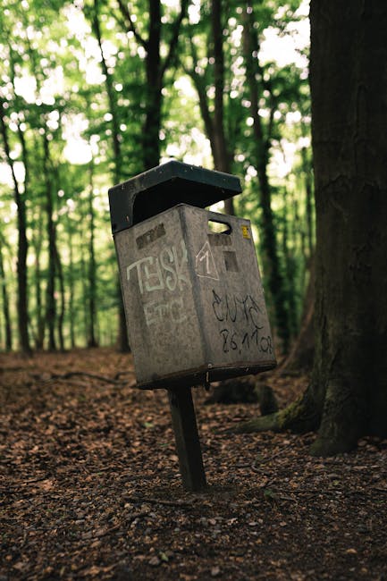 A person wearing a white glove and a wristwatch is holding a large white sack filled with a mix of garden waste and small debris, including twigs, leaves, and gravel. The scene appears to take place outdoors on a paved or gravel surface, with a metal shovel resting on top of the collected waste, partially visible in the upper left corner. The background includes a patch of green foliage and some scattered small items on the ground. The image relates to waste collection and disposal services, showcasing the process of gathering garden or outdoor rubbish, which might be handled by private waste removal providers like Waste Disposal Streatham, as part of alternative waste handling options.